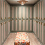 Interior view of a minimalist locker room with green cabinets and a floral bench.