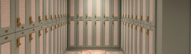 Interior view of a minimalist locker room with green cabinets and a floral bench.
