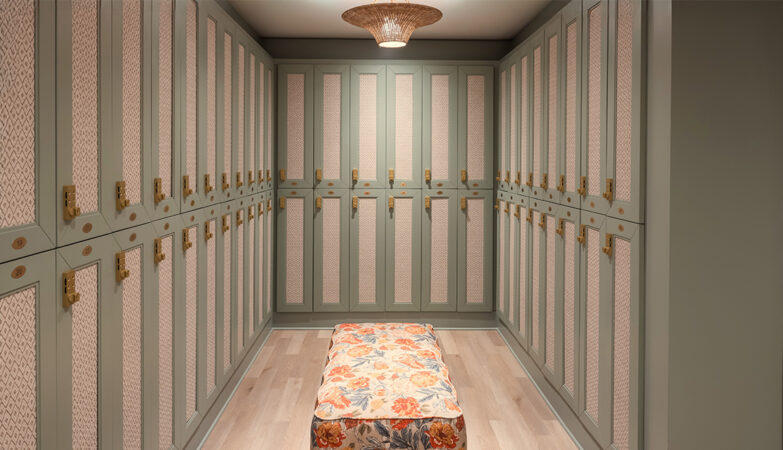 Interior view of a minimalist locker room with green cabinets and a floral bench.